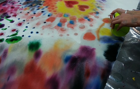 taideterapeuttinen värikäs maalattu kuva johon kuvassa lisätään suihkepullolla vettä